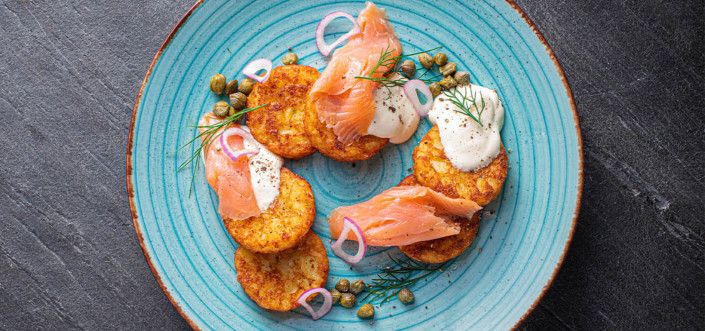 AVIKO Rösti pancakes fried in a pan with sour cream, salmon and dill